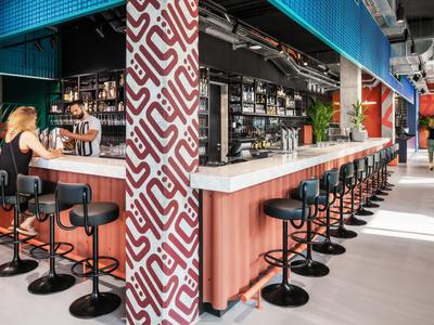 Modern hotel bar area with black bar stools and patterned column element