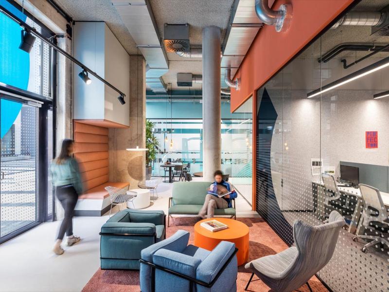 Moderní hotelová lobby s posezením, velkými okny a zasedací místností se skleněnou stěnou.