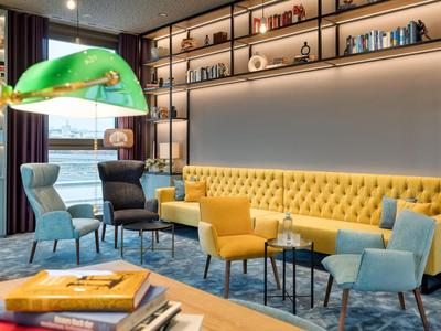 Modern eingerichteter Hotel-Lounge-Bereich mit gelbem Sofa und bunten Sesseln.