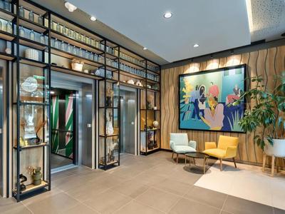 Moderner Hotel-Eingangsbereich mit Sitzgelegenheiten, dekorativen Regalen und farbenfroher Kunst an der Wand