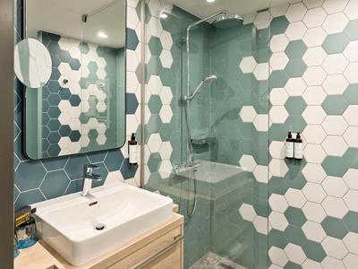 Modernes Badezimmer mit hexagonalen Fliesen, Waschtisch und begehbarer Dusche.