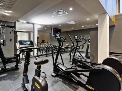 Moderner Fitnessraum mit Trainingsgeräten und Spiegelwand in einem Hotel.