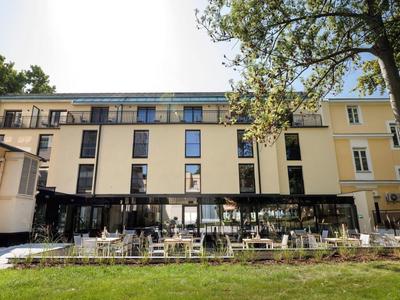 Modernes mehrstöckiges Gebäude mit großflächigen Fenstern und davor grünem Rasen.