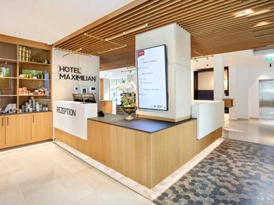 Reception area in a modern hotel with wood paneling and digital display.