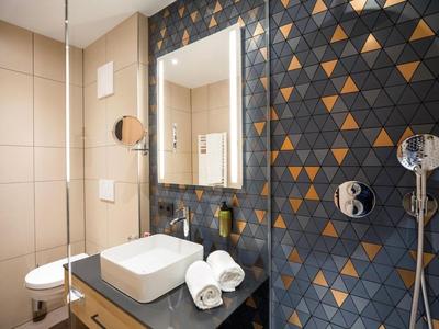 Modern bathroom with sink, towels, and blue and orange triangular wall tiles.