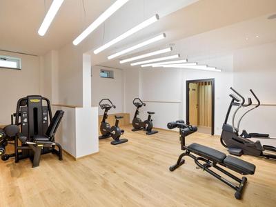 Bright gym with modern exercise equipment and wooden flooring.