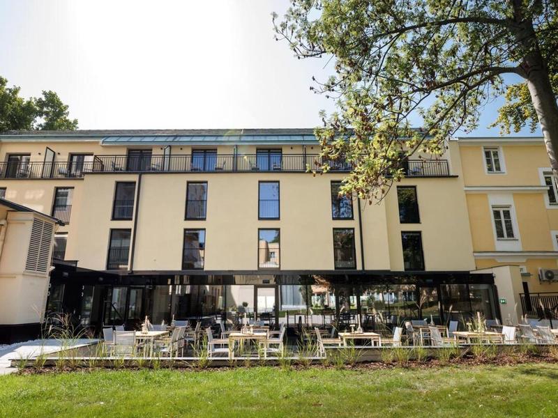 Moderní budova hotelu s terasou a zelenou zahradou vepředu