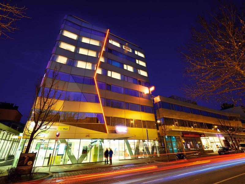Bâtiment d'hôtel moderne la nuit avec fenêtres éclairées et éclairage de rue.