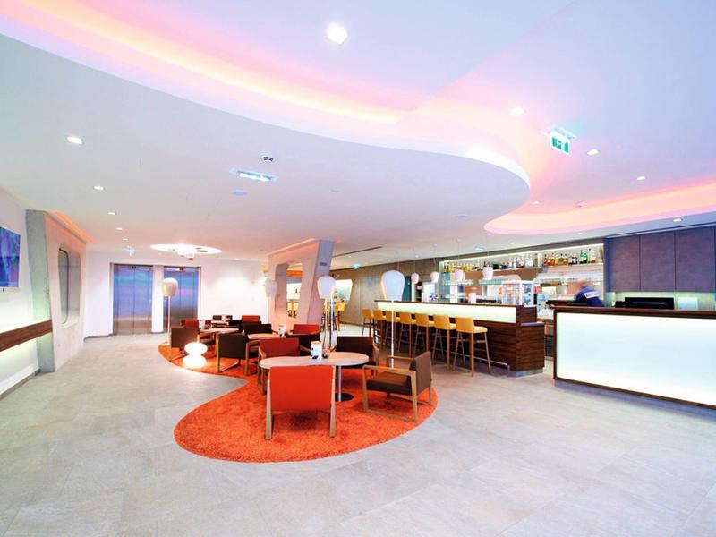 Espace lounge d'hôtel moderne avec bar, sièges et éclairage chaleureux.