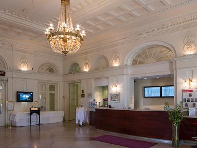 Eleganter Hotel-Empfangsbereich mit Kronleuchter, Rezeption und Sitzmöglichkeiten.