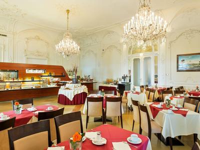 Eleganter Frühstücksraum mit Kronleuchtern und gedeckten Tischen mit roten und weißen Tischdecken.