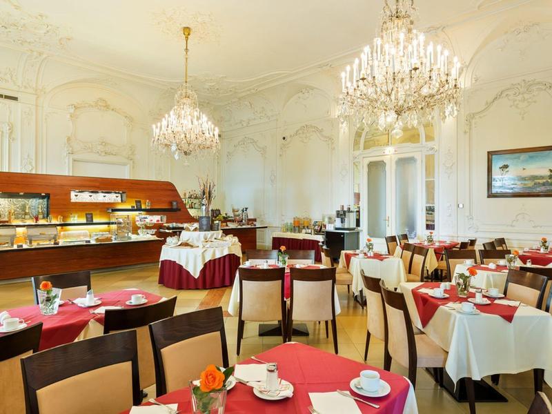 Eleganter Speisesaal mit Kronleuchtern, gedeckten Tischen und warmem Holzboden.