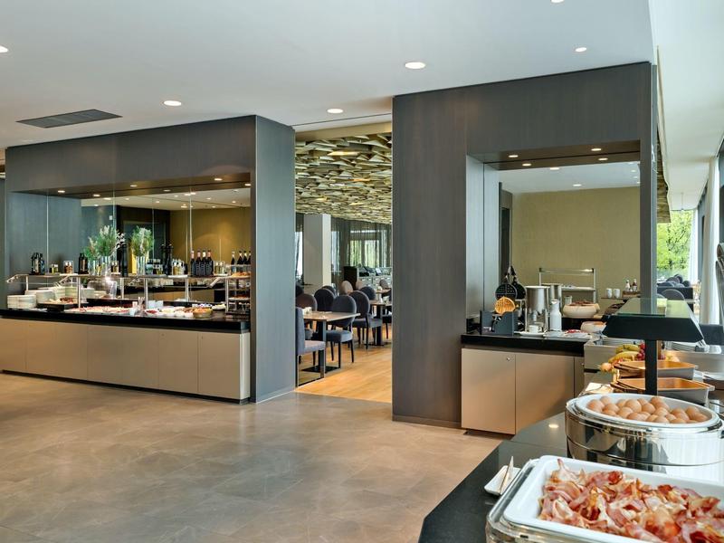 Sala da pranzo moderna dell'hotel con buffet e ospiti sullo sfondo.