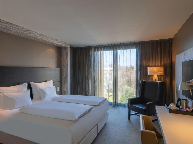 Camera d'hotel moderna con letto grande, scrivania e finestra con vista esterna.