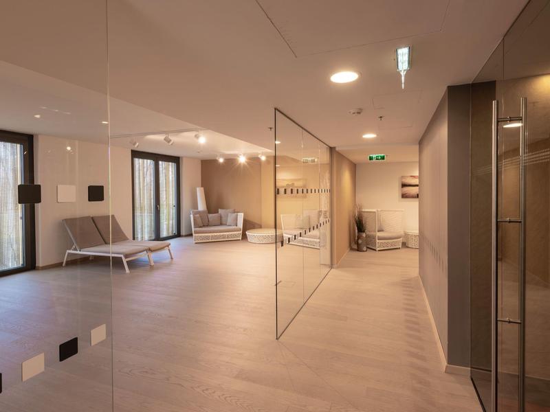 Area lounge moderna dell'hotel con posti a sedere, pavimento in legno e illuminazione sobria.