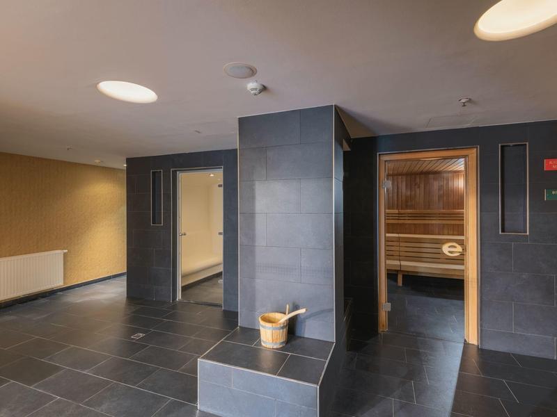 Area spa moderna con sauna, piastrelle nere alle pareti e panche per il relax.