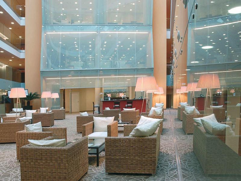 Modern hotel lounge area with wicker furniture and large glass walls.