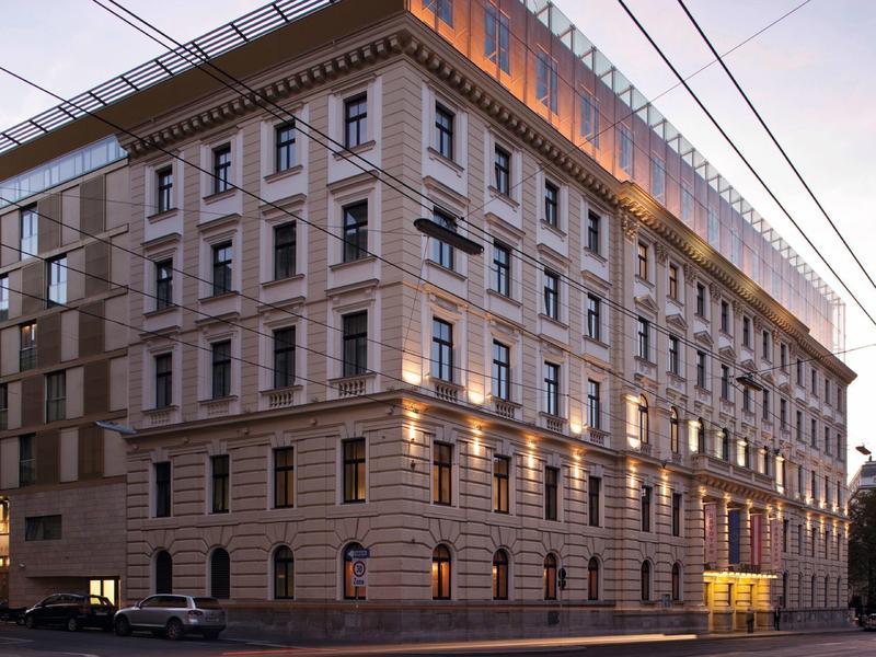 Illuminated historic building on a street corner at dusk.
