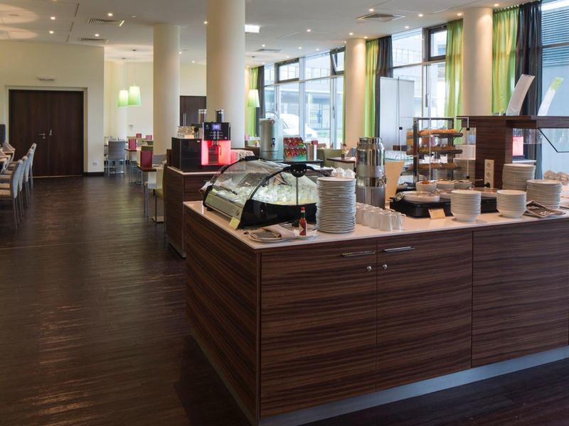 Cafetería moderna y luminosa con mostrador de madera, áreas de asiento y gran ventana con luz natural.