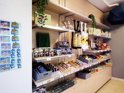 Prodejní police v obchodě se suvenýry s různými produkty a magnety na zdi.