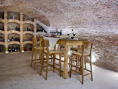 Cozy wine cellar with wooden table and chairs in a vaulted brick room.