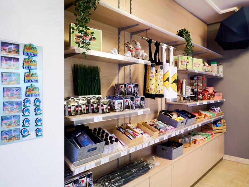 Prodejní police v obchodě se suvenýry s různými produkty a magnety na zdi.