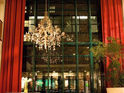 Lobby d'hôtel élégante avec grandes fenêtres, rideau rouge, lustre et coin salon.
