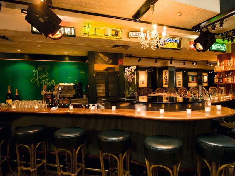 Gezellige bar met houten toonbank, krukken en warme verlichting.