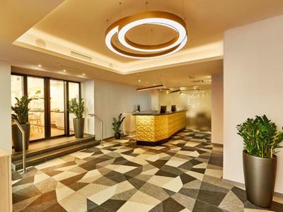 Moderner Hotel-Lobbybereich mit geometrischem Bodenmuster und beleuchtetem Rundlicht an der Decke.