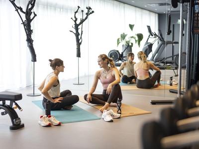 Dwie kobiety odpoczywają na matach do jogi po treningu w nowoczesnej siłowni.