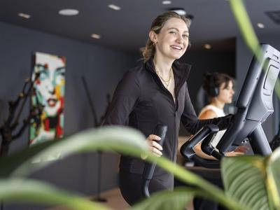 Kobieta ćwicząca na bieżni w nowoczesnej siłowni hotelowej.