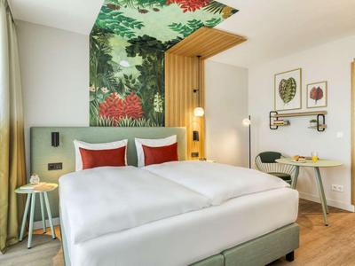 Modern hotel room with double bed, colorful wall decor, and a cozy atmosphere.