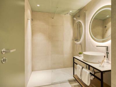 Modern bathroom with walk-in shower, round mirror, and sink on dark cabinet