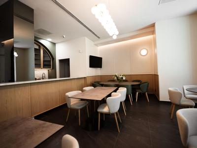 Restaurant moderne avec boiseries, chaises blanches et éclairage chaud.