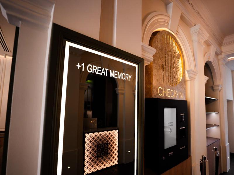 Elegante Hotelfassade mit beleuchtetem Schild und goldener Schrift im Innenbereich.