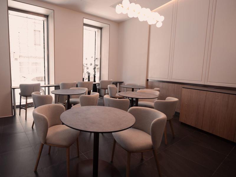 Modernes, helles Hotelrestaurant mit runden Tischen und bequemen Stühlen.