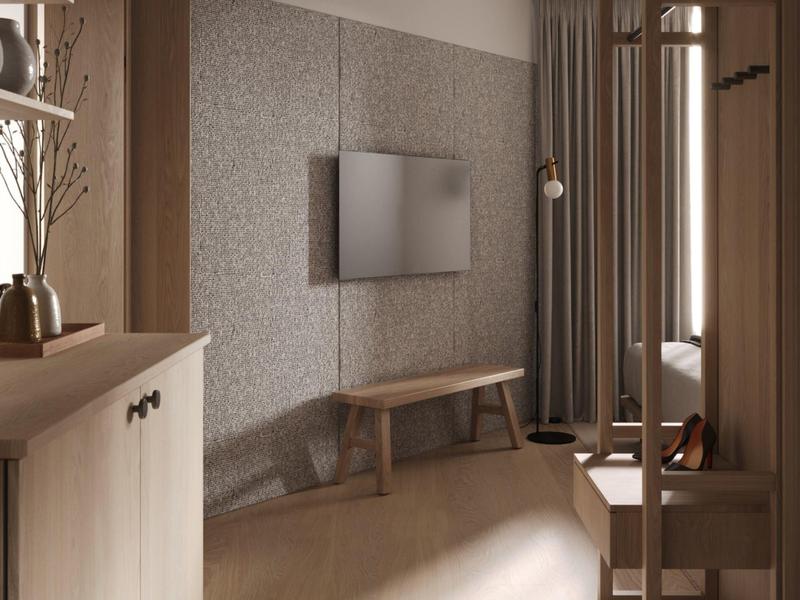 Modernes Hotelzimmer mit TV an grauer Wand, Holzbank und Garderobe bei Tageslicht.