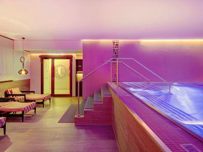 Moderner Wellnessbereich mit beleuchtetem Pool und entspannenden Lounge-Sesseln.
