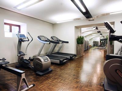 Siłownia z bieżniami i sprzętem do ćwiczeń na parkiecie i białych ścianach