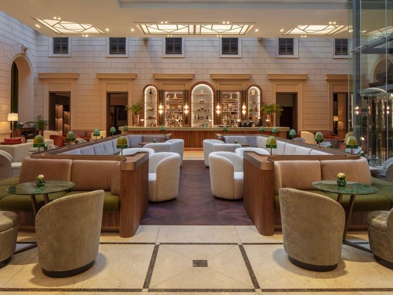 Elegante Hotellobby mit Sesseln, Sofas und einem stilvollen Barbereich im Hintergrund.