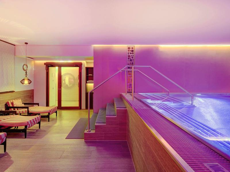 Moderner Wellnessbereich mit beleuchtetem Pool und entspannenden Lounge-Sesseln.