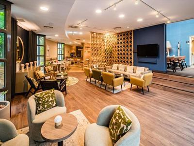 Espace lounge d'hôtel moderne avec des sièges confortables et un sol en bois.