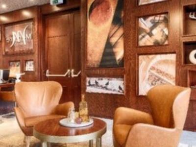 Gemütliche Sitzecke mit zwei beigen Sesseln und rundem Holztisch in eleganter Hotellobby.