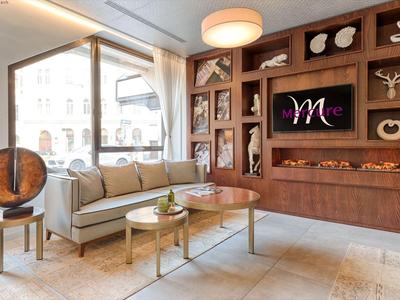 Modern eingerichteter Hotel-Loungebereich mit Sofa, Couchtischen und dekorativem Wandregal.