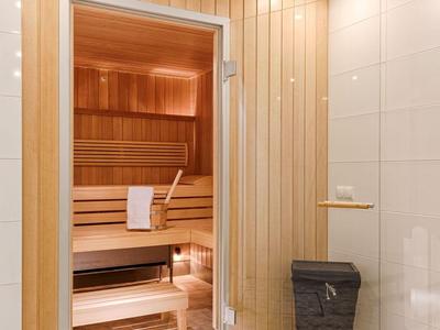 Heller Saunabereich mit Holzvertäfelung, Holzbank und einem Eimer für Wasser.