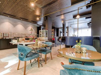 Modernes Hotelrestaurant mit runden Tischen, blauen Stühlen und elegantem, warmem Ambiente.