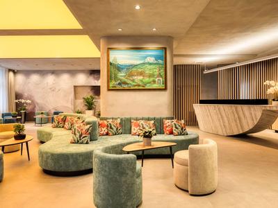 Moderner Hotel-Loungebereich mit geschwungenem Sofa, Kunst an der Wand und warmem Licht.