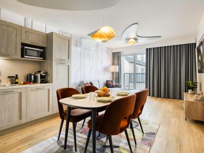Moderner Essbereich mit Holztisch, braunen Stühlen und Küchenzeile in hellem Apartment.