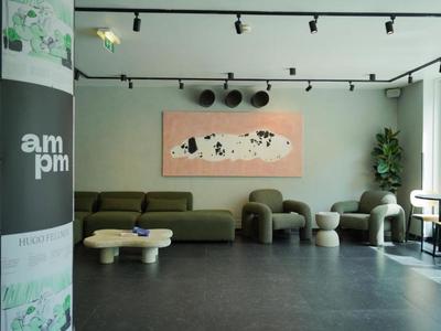 Lounge d'hotel moderna con divano grigio, sedute uniche e arte murale.
