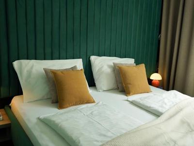 Camera d'hotel moderna con due letti, parete verde e tende beige.